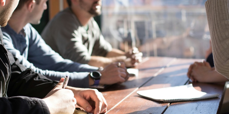 Hands and arms of staff in the workplace in a meeting, signifying sexual harrassment and employer's obligations in the workplace.